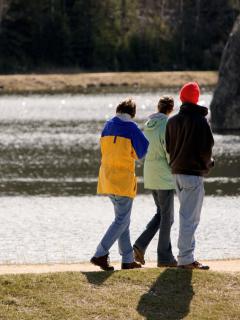 Bilde av tre personer langs en elv