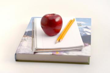 Bilde av eple, bok og blyanter